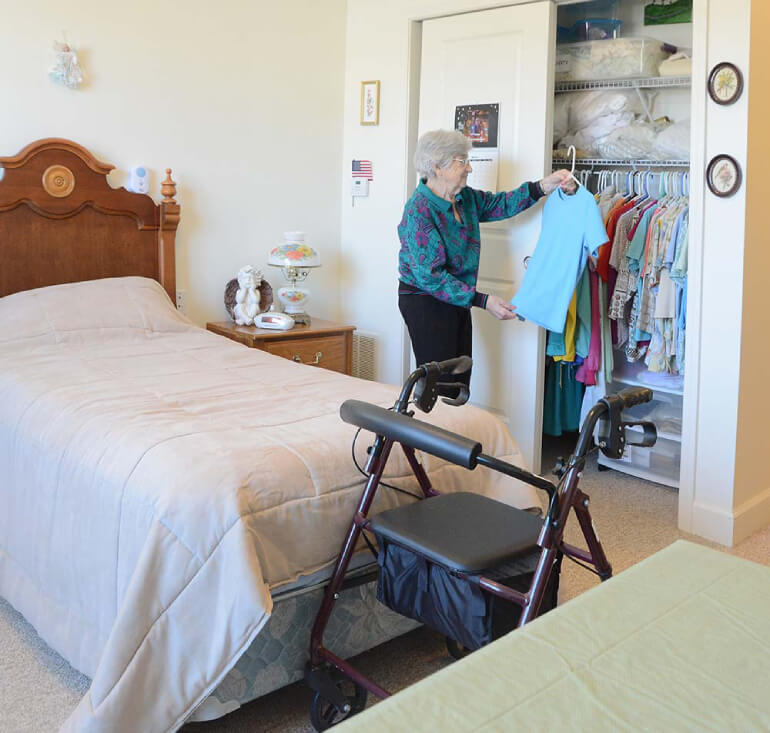resident hangs clothes up in their room