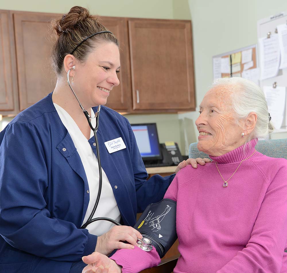 nurse taking a pulse reading smiling at a resident