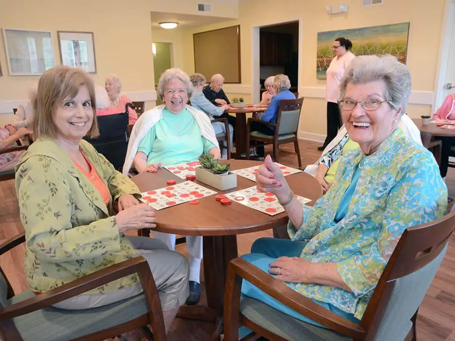 community members show thumbs up to the camera as they demonstrate a board game being played